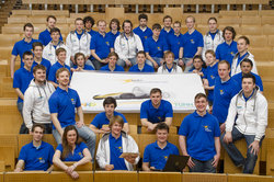 Das e-gnition-Team im Hörsaal der Technischen Universität Hamburg-Harburg mit einem Banner der Design-Studie des Elektrorennwagens
